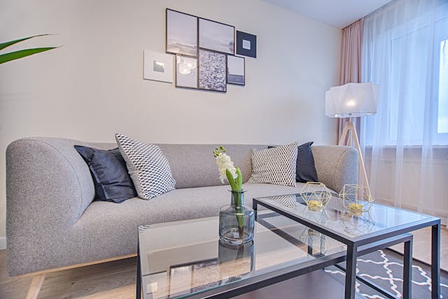 A white living room with a grey couch a glass coffee table